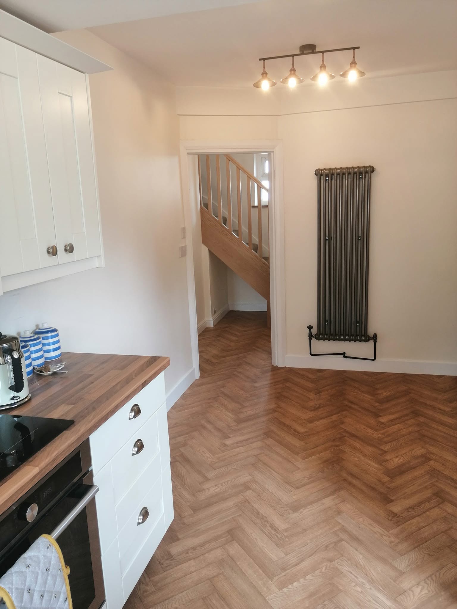 Leeds kitchen redecoration with white cabinets, herringbone wood flooring and a dark radiator